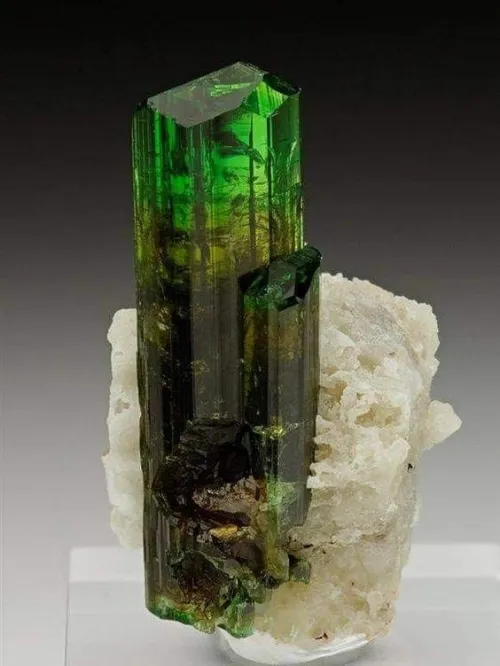 Emerald bracelet interacting with various metal textures in natural light