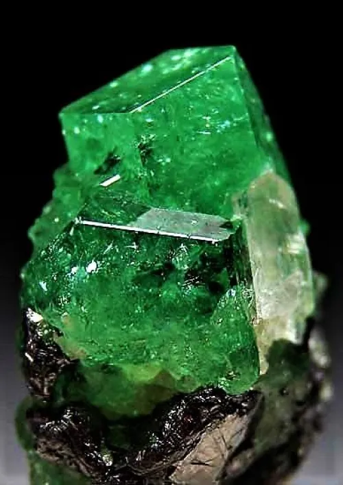 Hand cleaning an emerald pendant with soft cloth under lamplight